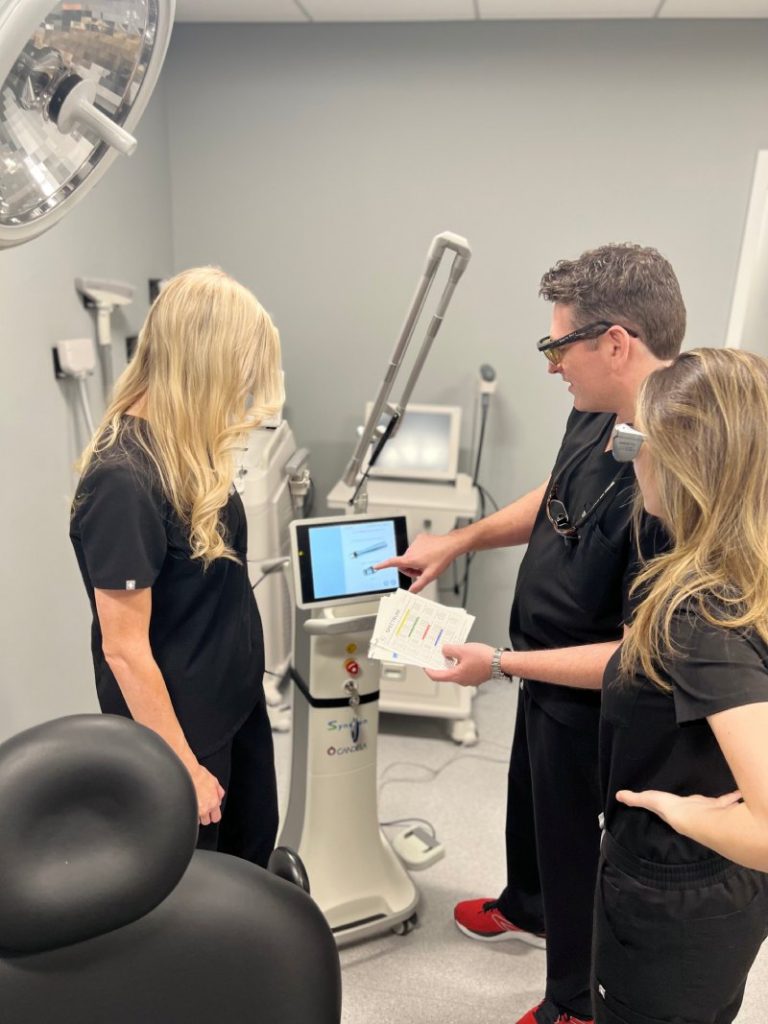 A photo of Nichole and Dr. Landmann looking at the Anti-aging Hands Treatment device.
